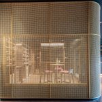 A contemporary wine tasting space features M22-83 brass woven wire mesh as a space divider for a tasting room.