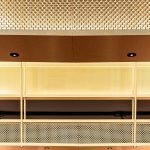 A contemporary wine tasting space features M22-83 brass woven wire mesh as a ceiling gantry that forms a sculptural canopy above the bar.