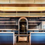 A contemporary wine tasting space features M22-83 brass woven wire mesh as a ceiling gantry that forms a sculptural canopy above the bar.