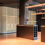 A contemporary wine tasting space features M22-83 brass woven wire mesh as a space divider for a tasting room.