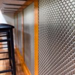 Discover how Banker Wire's M33-2 woven wire mesh adds texture, depth, and sophistication to this custom home bar remodel, creating a striking architectural focal point.